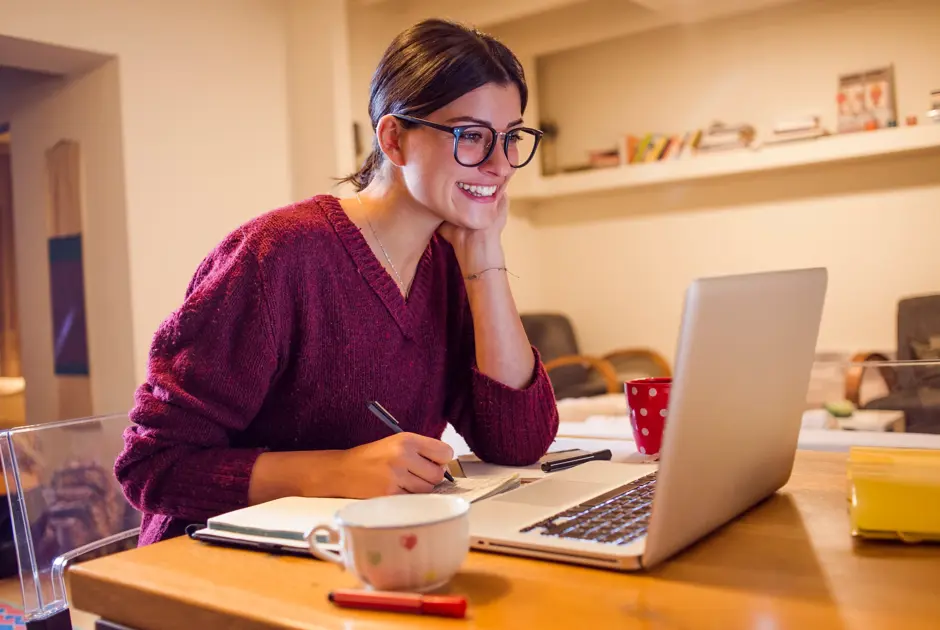 Female professional taking notes on paper while watching a webinar on her laptop