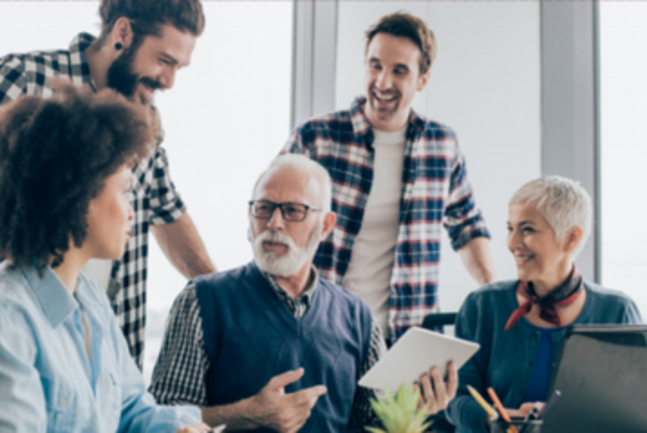 A diverse group of five colleagues, with two women and three men, are engaging in a lively discussion at an office table, exuding a sense of teamwork and collaboration.